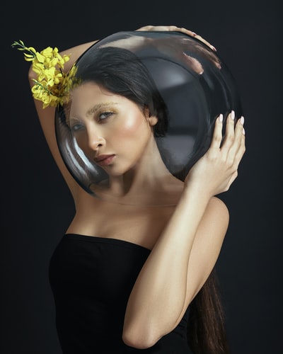 黑色抹胸款的女人举着黄色的花
